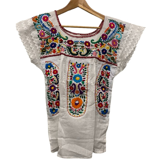 White embroidered top with colorful patterns on a wooden hanger against a plain background