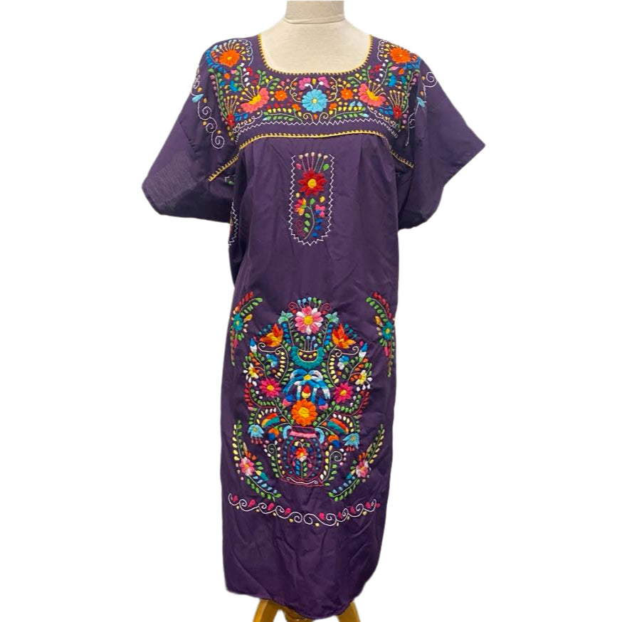 Purple dress with colorful embroidery on a mannequin against a white wall.