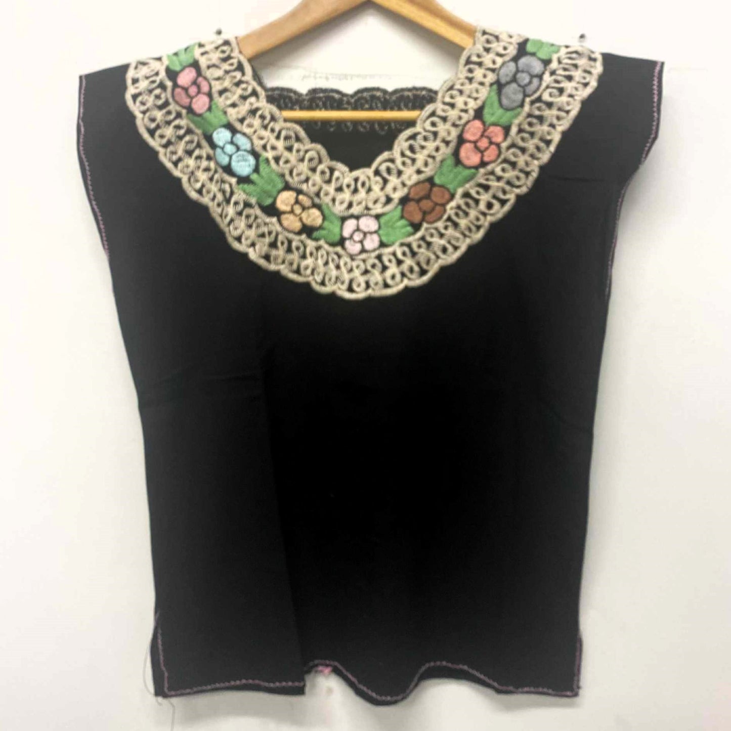 Black top with colorful floral embroidery on a white background