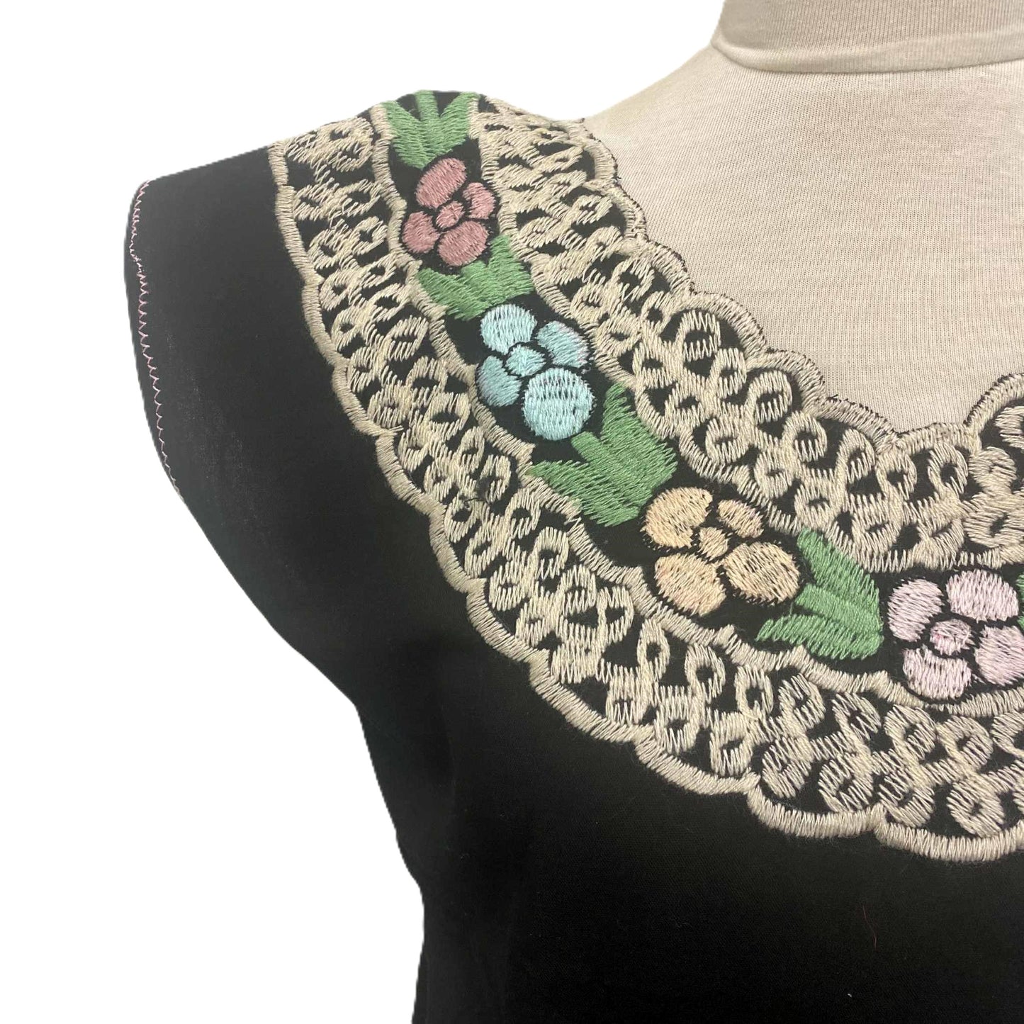 Black sleeveless top with floral embroidery on a mannequin